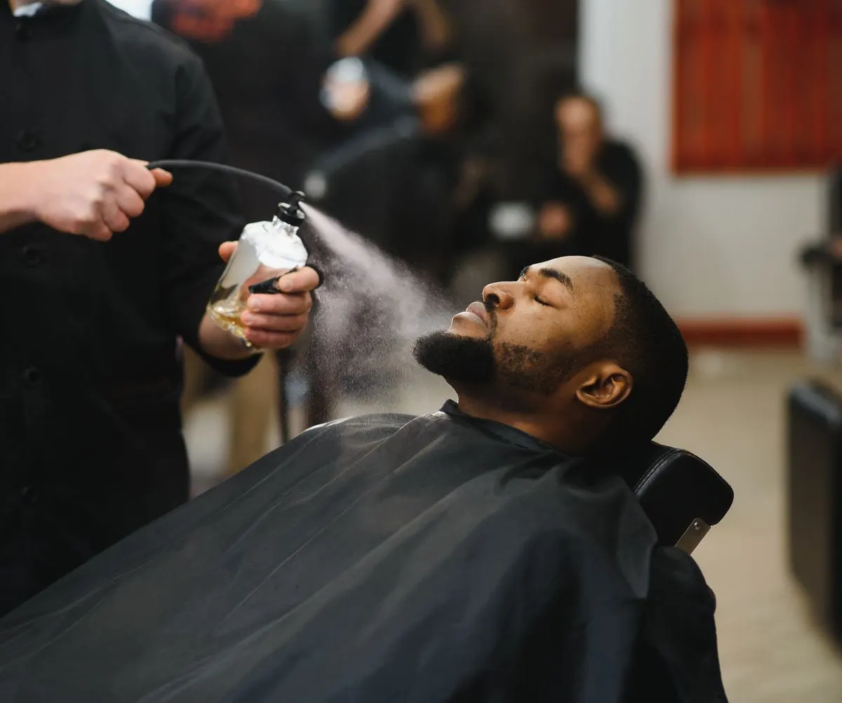A barber at work in a dark, panelled shop.
