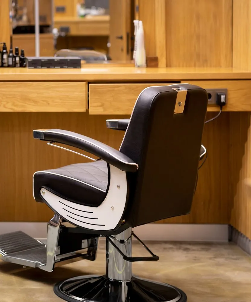 A barber's chair in warm wood-panelled light.